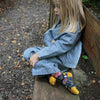 Child wearing a blue striped outfit sitting on a wooden bench outdoors.