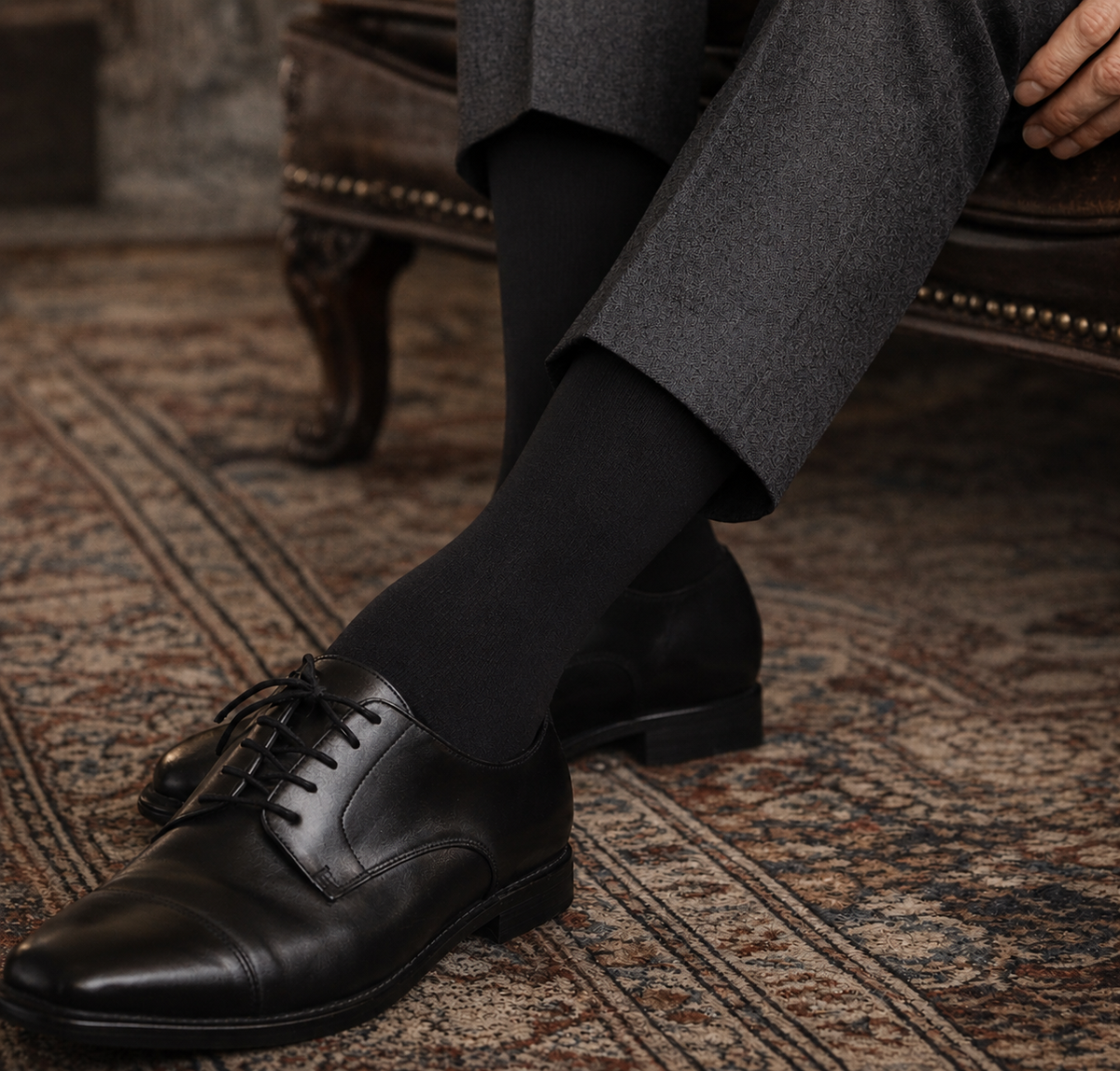 Person wearing black dress shoes and black socks on a patterned rug.
