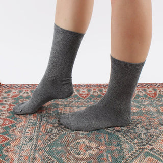 woman wearing navy marl socks on a patterned rug