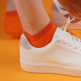 man wearing orange cotton trainer socks with white trainers