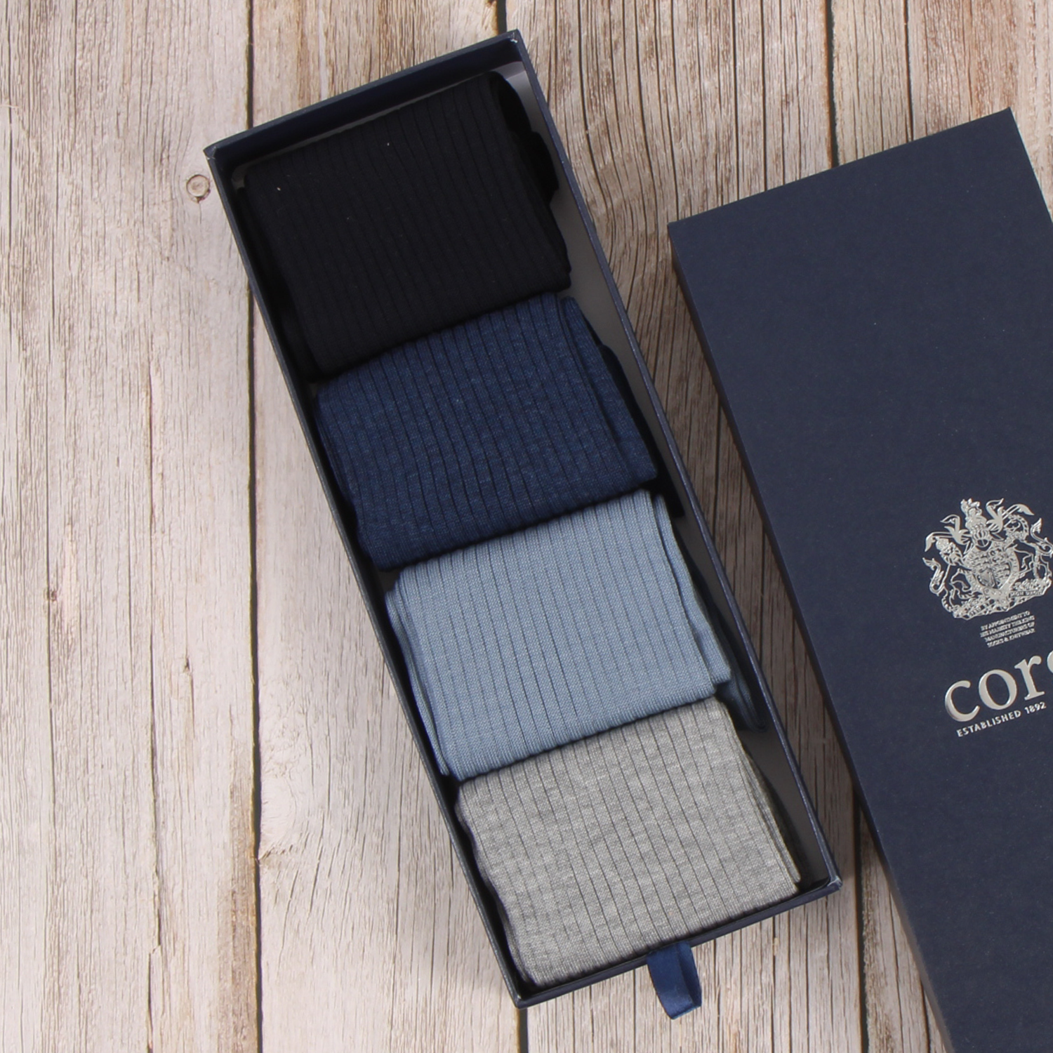 Set of three pairs of socks in a Corgi box with a visible brand logo on a wooden surface.