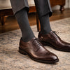 Brown dress shoes with charcoal Penarth socks on a patterned rug