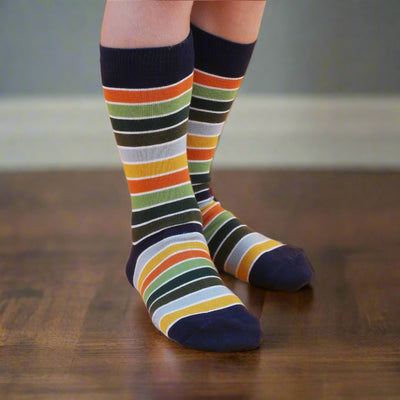 A pair of striped socks on a child's feet against a yellow background, showcasing the socks' colorful pattern.