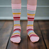 A pair of striped cotton socks on a child's feet, featuring multiple colors including blue, orange, and pink.