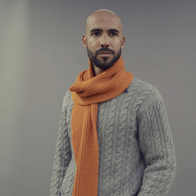 Man wearing a grey sweater and vicuna scarf against a grey background