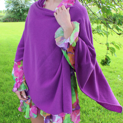 Person wearing a purple poncho with colorful sleeves in an outdoor setting