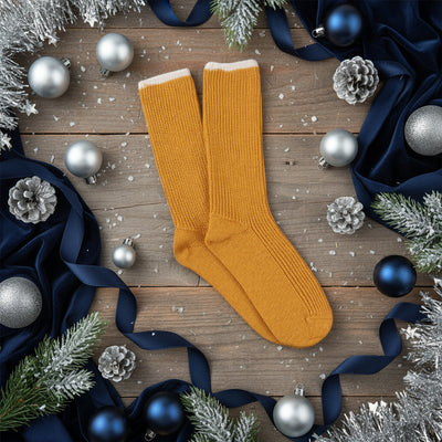 A pair of yellow slouch socks made from cashmere and cotton, showing the ribbed texture and contrast tipping.